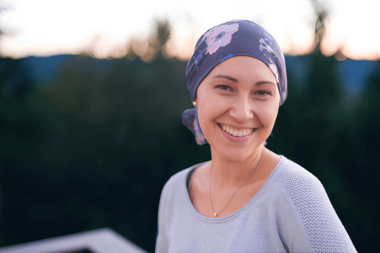 Una giovane donna che porta il foulard dopo la chemioterapia ma sorride perchè è guarita dal tuore al seno