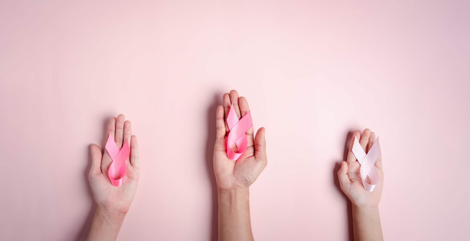mani di persone che tengono nastri rosa su sfondo rosa, consapevolezza del cancro al seno, giornata mondiale del cancro, giornata nazionale dei sopravvissuti al cancro nel concetto di febbraio.